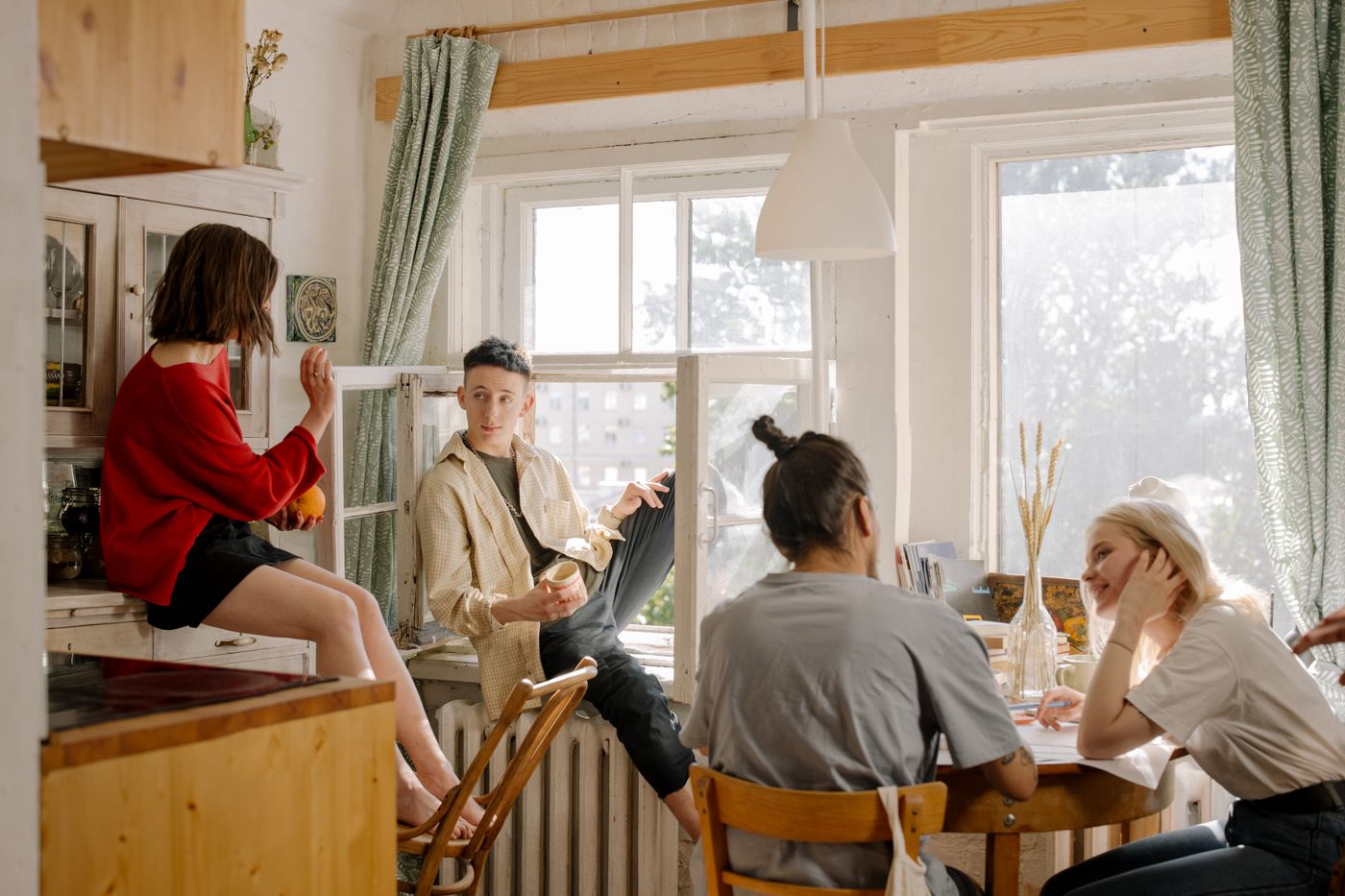 Cuatro jóvenes compartiendo la cocina de un apartamento, cada uno en lo suyo